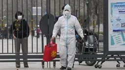 Pekerja dengan APD membantu menyerahkan tas dari penduduk di dalam komunitas yang lockdown di Beijing, Minggu (13/3/2022). Pihak berwenang menangguhkan layanan bus ke Shanghai setelah jumlah kasus baru covid-19 di timur laut China meningkat tiga kali lipat pada hari Minggu. (AP Photo/Ng Han Guan)