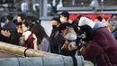 Pria memegang anjing berdoa di kuil Yushima Tenmangu di Tokyo pada Hari Tahun Baru, Jumat (1/1/2021). Warga di Tokyo ramai-ramai mengunjungi Kuil Yushima Tenmangu untuk berdoa dengan menulis harapan di papan Ema. (AP Photo/Hiro Komae)