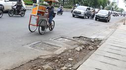 Pedagang melintasi bekas galian gorong-gorong di Jalan Hayam Wuruk, Jakarta, Rabu (20/2). Tidak maksimalnya perbaikan pascapembongkaran gorong-gorong menyebabkan trotoar di kawasan itu rusak dan dipenuhi kerikil serta batu (Liputan6.com/Immanuel Antonius)