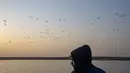 Burung air terlihat di belakang nelayan di lahan basah Bendungan Pong di Nagrota Suriyan, sekitar 65 kilometer selatan Dharmsala, India, Selasa (15/2/2022). Lahan Basah Pong menampung dan mendukung ratusan burung yang bermigrasi spesies di bulan-bulan musim dingin. (AP Photo/Ashwini Bhatia)