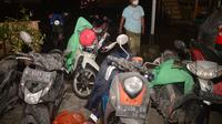 Seorang warga berjalan melewati sepeda motor para pengungsi yang diselimuti abu vulkanik pasca erupsi Gunung Semeru di desa Sumberurip, Lumajang (4/12/2021). Wakil Bupati Lumajang Indah Masdar melaporkan ada satu orang yang meninggal dunia akibat erupsi Gunung Semeru. (AFP/Juni Kriswanto)