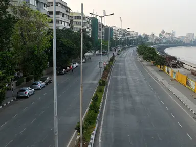 Jalan sepi di Marine Drive terlihat selama pembatasan yang diberlakukan oleh pemerintah negara bagian di tengah meningkatnya kasus corona Covid-19, di Mumbai, Kamis (15/4/2021). Kasus virus corona baru di India mencapai rekor tertinggi pada Rabu, 14 April. (Punit PARANJPE / AFP)