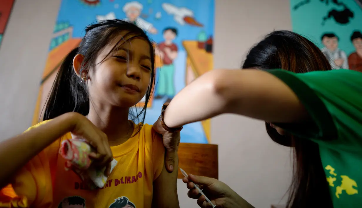 Seorang siswi meringis saat disuntikkan vaksin anti-dengue di Sekolah Dasar Parang di Marikina, sebelah barat Manila, Senin (4/4). Filipina telah menyuntikkan vaksin pertama di dunia untuk penyakit DBD itu kepada 1 juta pelajar. (NOEL CELIS/AFP)
