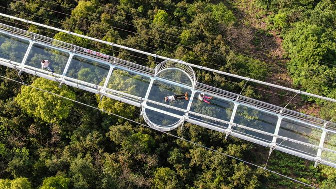 Foto yang diambil pada 4 Mei 2019 menunjukkan orang-orang mengunjungi jembatan berlantai kaca di Huaxi Adventure Park, Provinsi Jiangsu timur China. Jembatan kaca setinggi 518 meter ini menjadi tujuan wisata favorit di China. (Photo by STR / AFP)