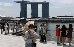 Seorang pengunjung, yang mengenakan masker pelindung di tengah kekhawatiran tentang penyebaran Virus Corona COVID-19, berjalan di sepanjang Merlion Park di Singapura pada 17 Februari 2020. (Roslan RAHMAN / AFP)