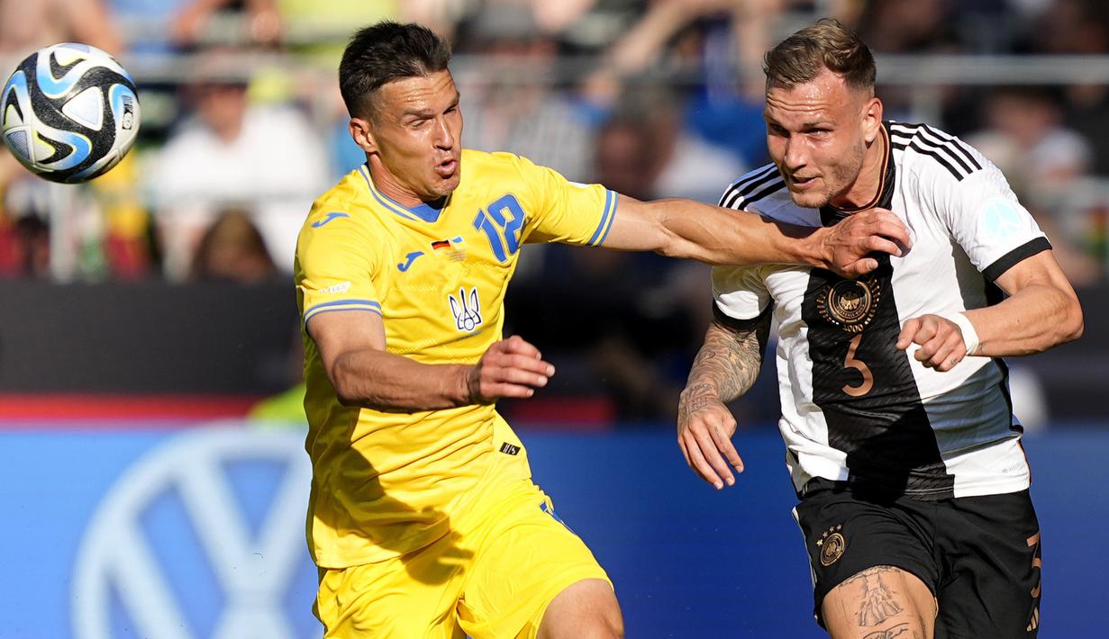 Pemain Timnas Jerman, David Raum (kiri), berebut bola dengan pemain Timnas Ukraina, OleksandrTymchyk, dalam laga persahabatan internasional FIFA Matchday 2023 yang digelar di Weserstadion, Bremen, Senin (12/6/2023) malam WIB. (AP Photo/Martin Meissner)