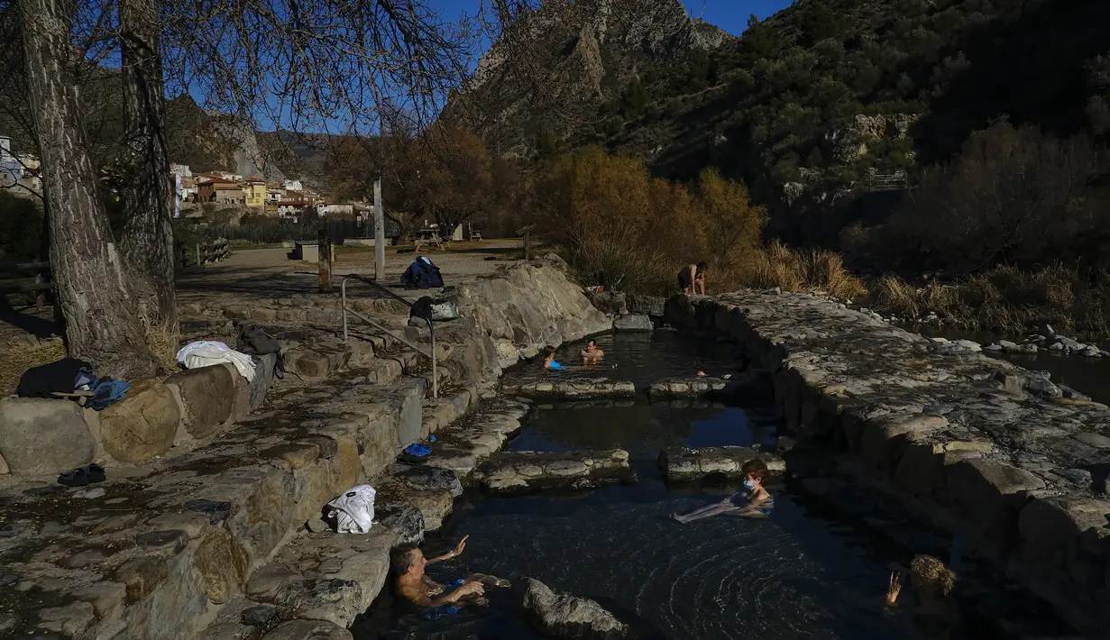 Sejumlah warga menikmati pemandian air panas alami Sungai Cidaco pada hari musim dingin di desa kecil Arnedillo, Spanyol utara (18/1/2022). Pemandian air panas alami Sungai Cidaco memiliki suhu 35 derajat Celcius (95 derajat Fahrenheit). (AP Photo / Alvaro Barrientos)