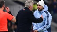 Pelatih Real Madrid asal Italia, Carlo Ancelotti, berbicara kepada putranya, asisten pelatih Davide Ancelotti (kanan) selama pertandingan Liga Champions UEFA antara Atalanta dan Real Madrid di Stadion Gewiss di Bergamo, pada 10 Desember 2024. (Marco BERTORELLO/AFP)