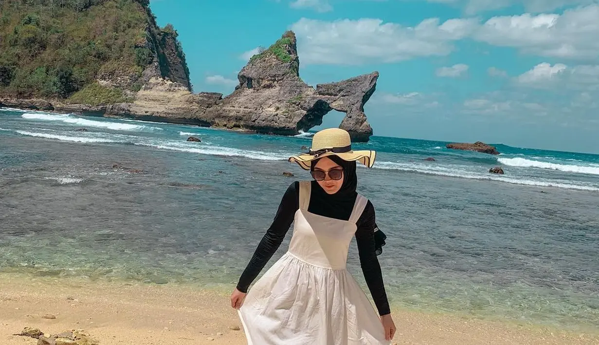 Mengenakan dalaman hitam lengan panjang tanpa motif plus hijab warna senada yang dipadu dengan terusan turangga tanpa lengan, Putri Delina makin modis berkat kacamata hitam. Mempercantik penampilannya di Pantai Atuh, pesohor dengan 3 jutaan pengikut di Instagram ini pakai topi bundar beraksen pita hitam berikut garis tepi yang mengitari topi. (Foto: Dok. Instagram @putridelinaa)