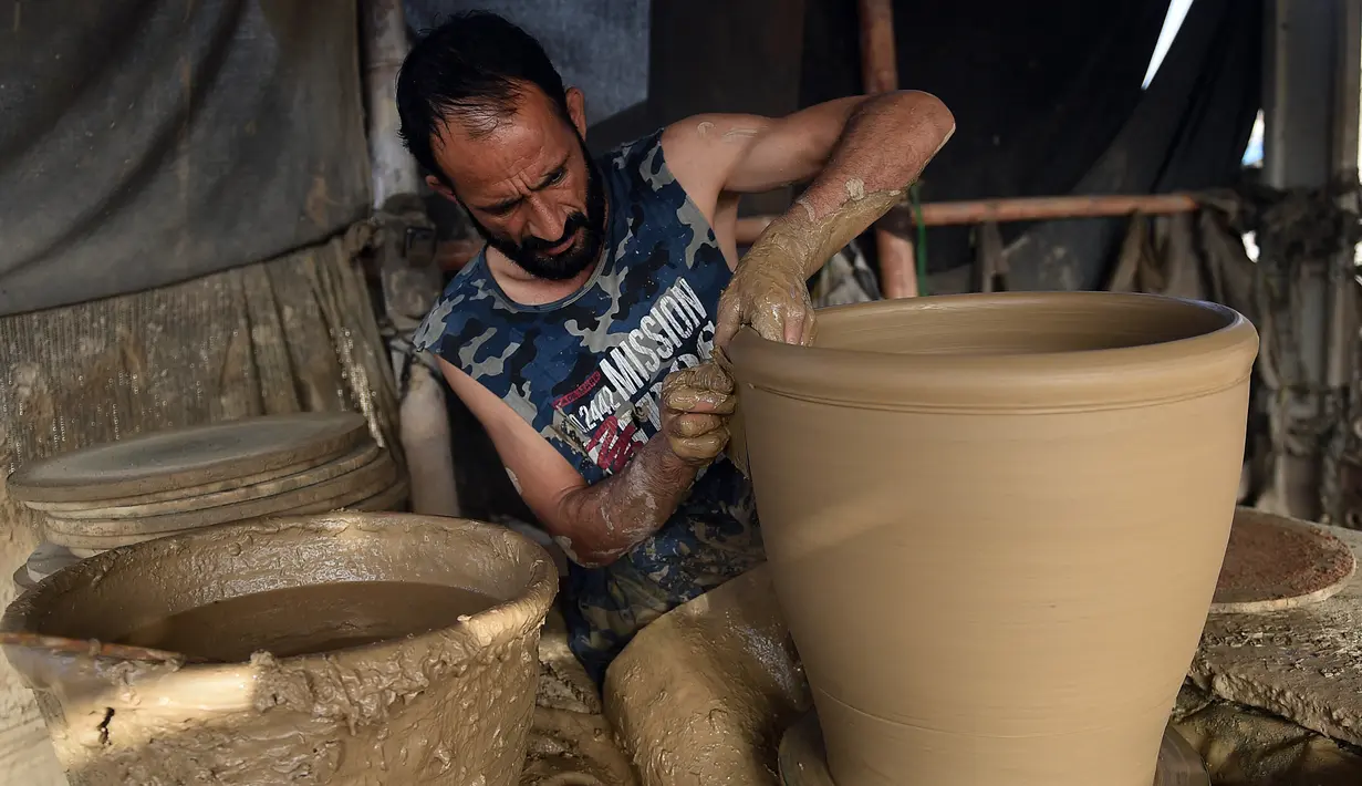 Seorang pembuat tembikar membuat pot tanah liat di sebuah bengkel di Karachi, Pakistan, Rabu (23/2/2022). (Rizwan TABASSUM/AFP)