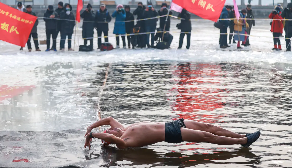 Seorang penggemar renang musim dingin menyelam ke danau yang sebagian beku di Shenyang, provinsi Liaoning, China pada 25 Januari 2022. Berenang di musim dingin adalah kegiatan olahraga yang jarang dijumpai kecuali di beberapa negara dengan musim dingin yang cukup panjang. (STR/AFP)