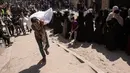 Seorang pria Palestina membawa sekantong tepung, sementara yang lain menunggu di depan titik distribusi yang didirikan oleh Save Youth Future Society (SYFS), yang bekerja sama dengan Program Pangan Dunia PBB (WFP), di Kota Gaza pada 26 Juni 2025. (BASHAR TALEB/AFP)