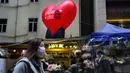 Orang-orang memakai masker berjalan melewati sebuah toko bunga pada Hari Valentine di Hong Kong, Jumat (14/2/2020). China  melaporkan peningkatan tajam dalam jumlah orang yang terinfeksi virus baru, ketika jumlah korban mendekati 1.400. (AP Photo/Vincent Yu)