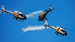 Aksi tim aerobatik Patrulla Aspa bermanuver menggunakan helikopter saat menghebohkan pengunjung di atas Pantai San Lorenzo di Gijon, Spanyol, Minggu (24/7). (REUTERS/Eloy Alonso)