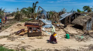 Seorang wanita melintasi rumah-rumah yang hancur akibat topan Kenneth pada bulan lalu di desa pesisir Guludo, Pulau Ibo, 13 Mei 2019. Umat Islam di Mozambik melalui bulan Ramadan dengan badai yang menyebabkan sebagian besar masjid hancur dan persediaan makanan sangat terbatas. (Zinyange Auntony/AFP)