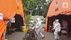 Petugas medis membawa pasien COVID-19 menuju tenda darurat di RSUD Bekasi, Rabu (23/6/2021). Tenda darurat didirikan sebagai upaya menambah ruang IGD yang dapat menampung 30 pasien menyusul ruangan di rumah sakit sudah penuh akibat lonjakan kasus Covid-19. (Liputan6.com/Herman Zakharia)
