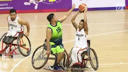 Pebasket difable Indonesia, Gusti Putu P Adriyana berebut bola dengan M Hafiz Ramli (Malaysia) pada laga Indonesia Para Games Invitational Tournament 2018 di Hall A Senayan, Jakarta, Minggu (1/7). Indonesia unggul 54-53. (Liputan6.com/Helmi Fithriansyah)