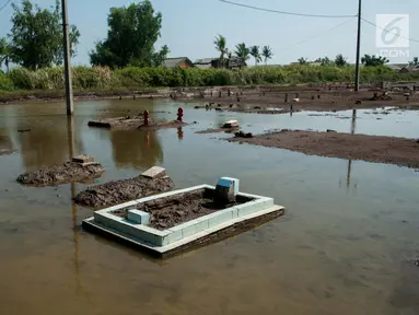 Suasana pemakaman yang terendam rob, di Desa Pantai Bahagia, Muara Gembong, Kabupaten Bekasi, Jawa Barat, Jumat (9/6). Banjir sering terjadi di kawasan tersebut dengan ketinggian air mencapai 50 cm.(Liputan6.com/Gempur M Surya)