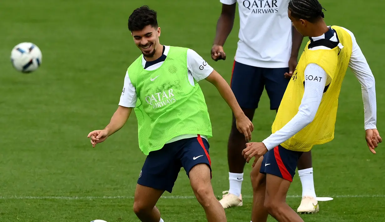 <p>Gelandang Paris Saint-Germain (PSG) Vitinha (kiri) berebut bola dengan rekannya, Hugo Ekitike (kanan) selama sesi latihan jelang melawan Monaco, di Saint-Germain-en-Laye, barat Paris pada 26 Agustus 2022. Laga PSG vs AS Monaco di lanjutan Ligue 1 Prancis akan berlangsung pada 29 Agustus 2022 dinihari WIB. (FRANCK FIFE / AFP)</p>