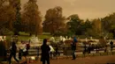 Langit yang tampak merah atau sepia menyelimuti Hyde Park di kota London, Inggris, Senin (16/10). Fenomena ini membuat sebagian warga heboh dan berusaha mengabadikan kondisi langit yang berwarna tak biasa tersebut. (AP Photo/Matt Dunham)