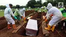Petugas menurunkan peti berisi jenazah yang dimakamkan dengan protokol COVID-19 di TPU Bambu Apus, Jakarta, Jumat (22/1/2021). Sejak dibuka Kamis (21/1) kemarin hingga hari ini, tercatat sekitar 35 jenazah dimakamkan dengan protokol COVID-19 di TPU Bambu Apus. (Liputan6.com/Helmi Fithriansyah)
