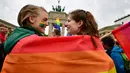 Dua wanita berselimut bendera pelangi saat demontrasi kaum LGBT di depan Gerbang Brandenburg di Berlin (30/6). Sebanyak 393 anggota parlemen Jerman menyetujui pernikahan sesama sejenis, dan 226 anggota lainnya menolaknya. (AFP Photo/Tobias Schwarz)