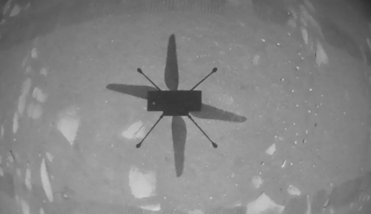 Helikopter Ingenuity melayang di atas permukaan planet Mars saat penerbangan pertama bertenaga dan terkontrol di planet lain pada 19 April 2021. h(Handout/NASA/JPL-CALTECH/AFP)