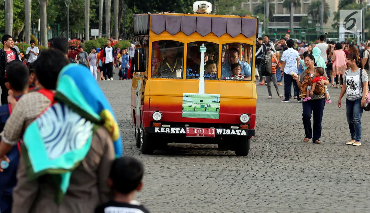 Sejumlah pengunjung menaiki kereta wisata di halaman Monumen Nasional, Jakarta, Rabu (27/6). Libur ketiga Lebaran dimanfaatkan warga untuk bekunjung ke lokasi wisata bersama keluarga. (Liputan6.com/Johan Tallo)