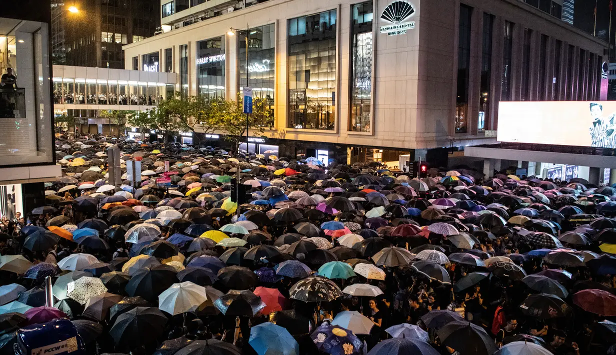 Ribuan pegawai negeri sipil (PNS) mengenakan payung saat mengikuti unjuk rasa menolak RUU Ekstradisi di Hong Kong, Jumat (2/8/2019). Unjuk rasa adalah yang pertama kalinya pegawai pemerintah mempromosikan demonstrasi di Hong Kong. (ANTHONY WALLACE/AFP)