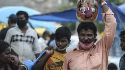Seorang pria membawa labu yang dilukis dengan wajah setan selama festival Hindu 'Durga Puja' di pasar grosir di Chennai (13/10/2021). Durga Puja juga disebut Durgotsab adalah festival tahunan di Asia Selatan untuk memuja dewi Durga dari agama Hindu. (AFP/Arun Sankar)