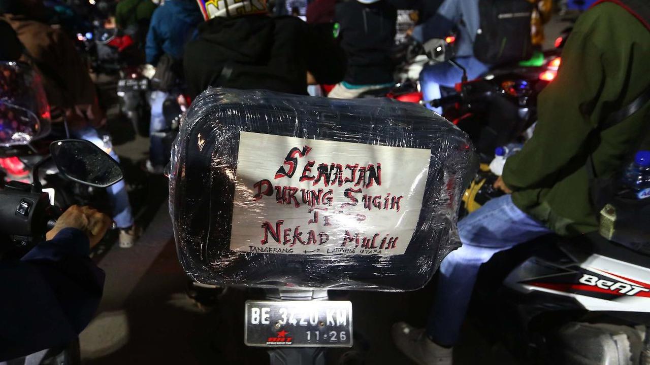 Sebuah tulisan terpasang pada bagian belakang sepeda motor pemudik di Pelabuhan Ciwandan, Cilegon, Banten, Sabtu (6/4/2024). Sejumlah pemudik menuliskan pesan-pesan unik bertema Lebaran yang dipasang di sepeda motornya. Liputan6.com/Angga Yuniar