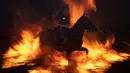 Seorang penunggang kuda melompati api unggun selama festival Luminarias di San Bartolome de Pinares, Spanyol, Rabu (16/1). Masyarakat meyakini tradisi itu dimulai ketika binatang mulai jatuh sakit tanpa penyebab yang jelas. (GABRIEL BOUYS / AFP)