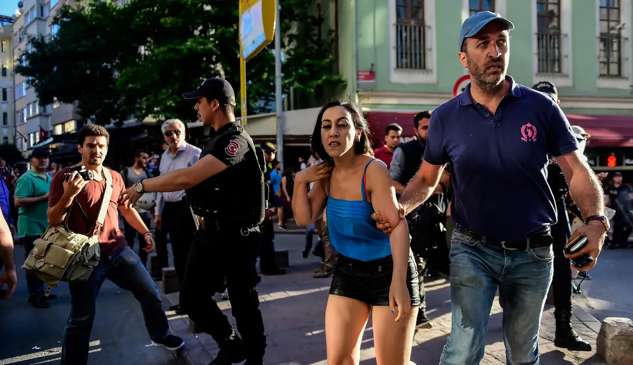 Petugas polisi anti huru hara berusaha menghalangi peserta pawai masuk ke lokasi parade Gay Pride di Istiklal Street Turki, pusat kota Istanbul, bertepatan dengan hari raya Idul Fitri 1438 Hijriah, Minggu (25/6). (YASIN AKGUL/AFP)