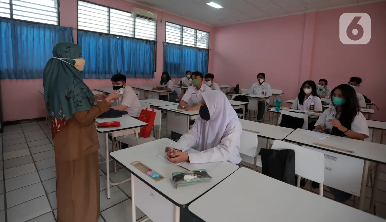 Guru mengajar saat uji coba pembelajaran tatap muka (PTM) terbatas di SMAN 1 Kota Tangerang, Banten, Senin (6/9/2021). Dinas Pendidikan Provinsi Banten uji coba PTM di SMA di Kota Tangerang secara terbatas dengan sistem bergiliran dan menerapkan protokol kesehatan ketat. (Liputan6.com/Angga Yuniar)