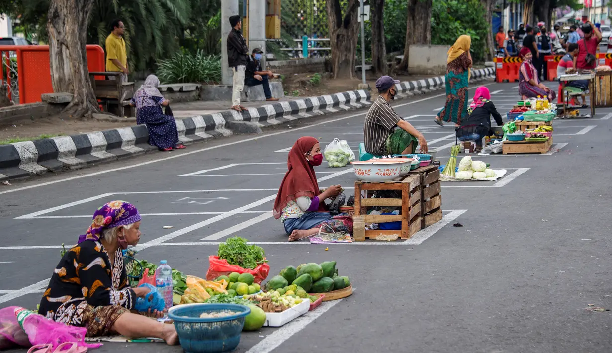 Pedagang menjual dagangannya di antara petak-petak untuk menerapkan jaga jarak (physical distancing) di sepanjang jalan di Surabaya, Selasa (2/6/2020). Garis petak-petak bagi pedagang itu sebagai langkah pencegahan penyebaran COVID-19. (Photo by Juni Kriswanto / AFP)