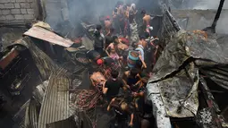 Warga berdesakan untuk mengumpulkan sisa kabel listrik serta barang yang masih terpakai usai kebakaran pemukiman padat penduduk dekat pelabuhan di Manila, Filipina, Selasa (9/5). Mereka berebut mengumpulkan tembaga dari sisa kabel listrik (TED ALJIBE/AFP)
