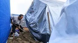 Seorang pria menggali dengan sekop di luar tenda di antara tenda-tenda lain yang didirikan oleh warga Palestina yang berlindung dari pemboman Israel di sekitar Rumah Sakit Nasser, di Khan Yunis di Jalur Gaza selatan pada 14 November 2023. (Mahmud HAMS/AFP)