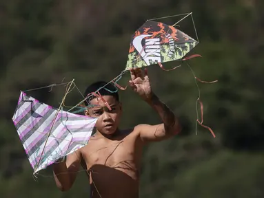 Seorang pemuda memegang layang-layang saat festival di favela Turano di Rio de Janeiro, Minggu, 7 Juli 2024. (AP Photo/Bruna Prado)