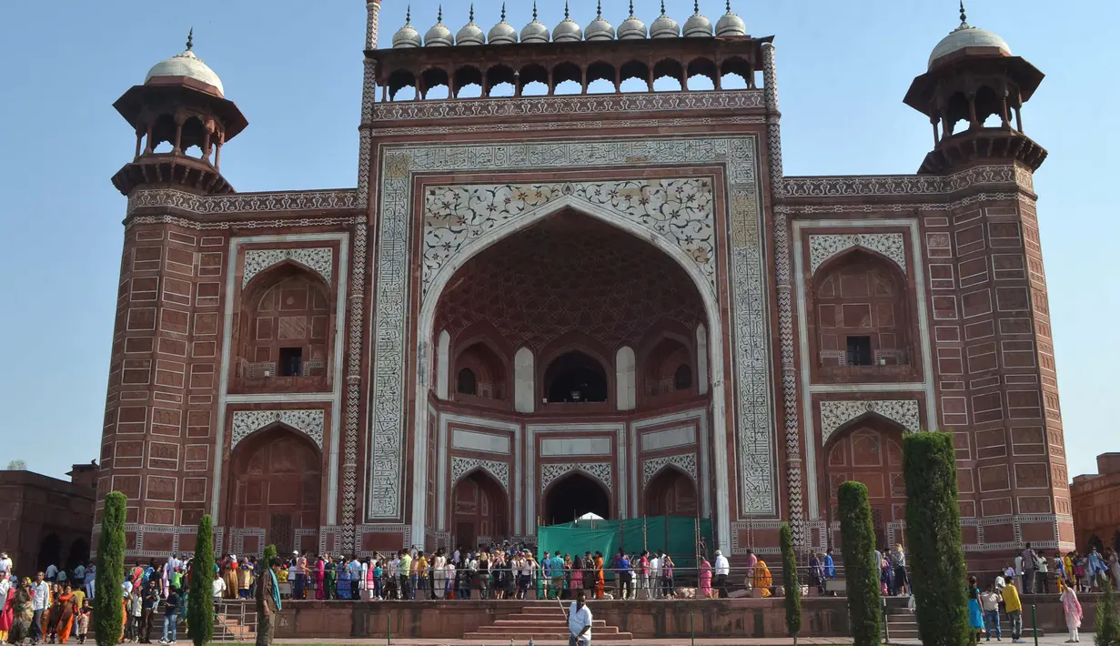Orang-orang berkumpul di sekitar royal gate atau gerbang kerajaan setelah pilar Taj Mahal (kedua kanan) runtuh di Agra, India, Kamis (12/4). Kendati demikian, hingga berita ini diturunkan tidak ada korban jiwa dalam peristiwa tersebut. (AFP Photo)