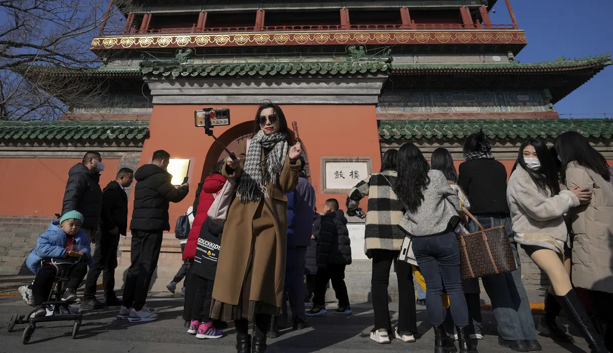 <p>Seorang perempuan berswafoto dengan haw China berlapis gula saat pengunjung berkumpul di luar Menara Drum di Beijing, Senin (30/1/2023). Orang-orang China menikmati Tahun Baru Imlek dan mengunjungi berbagai lokasi wisata di kota-kota di sekitar China setelah pencabutan pembatasan COVID-19 yang kejam bulan lalu, memungkinkan banyak aspek kehidupan normal kembali. (AP Photo/Andy Wong)</p>