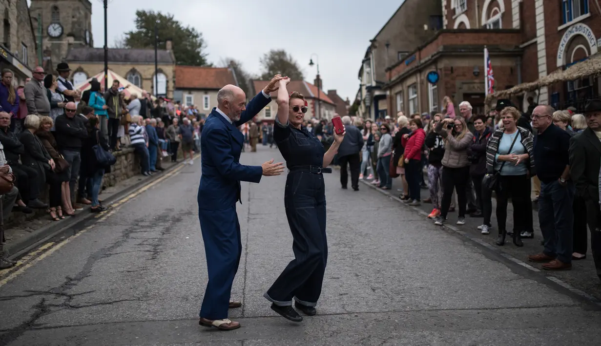 Reenactor Perang Dunia II menari saat mengikuti 'Railway in Wartime Event' yang ke 25 di Pickering, Inggris (15/10). Para reenactor ini melakukan semacam rekonstruksi sejarah dari Perang Dunia II. (AFP Photo/Oli Scarff)