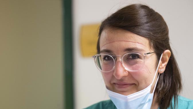 Elisabetta Teti, dengan bekas luka yang dalam di wajah saat memakai masker, tersenyum pada akhir pemeriksaan medis di unit sub-intensif COVID-19 Rumah Sakit Poliklinik Tor Vergata, di Roma , 7 November 2020. (AP Photo/Alessandra Tarantino)