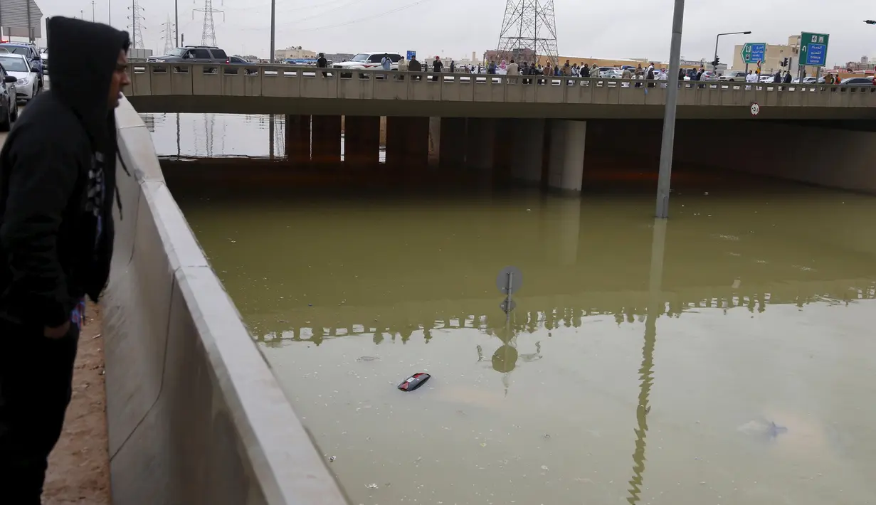Warga saat melihat lokasi tenggelamnya beberapa kendaraan yang berada dibawah fly over di Riyadh, Arab Saudi, (25/11). Hujan lebat yang mengguyur kota Riyadh menyebabkan banjir di sejumlah titik. (REUTERS/Faisal Al Nasser)