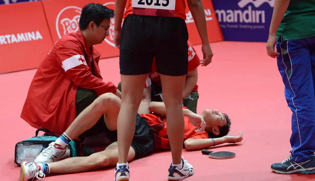 Petenis meja Indonesia, M Bima Abdi Negara terjatuh dan mendapat perawatan medis saat bertanding melawan pasangan Korea Selatan Lee Sangsu/Jeon Jihee di Asian Games 2018, Jakarta, Rabu (29/8). (ANTARA FOTO/INASGOC/Dewi Nurcahyani/ang/18)