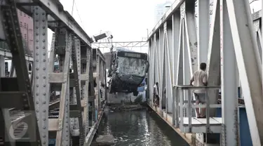 Petugas mengevakuasi bus transjakarta yang terperosok ke sungai usai ditabrak kereta Senja Utama Solo di perlintasan Jalan Mangga Dua, Jakarta, Kamis (19/5). Tak ada korban jiwa, namun sopir Transjakarta mengalami luka berat. (Liputan6.com/Faizal Fanani)