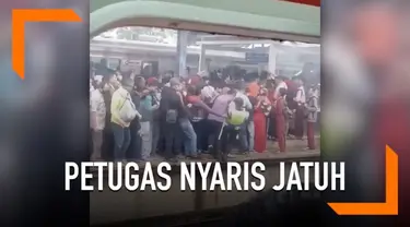 Desakan antrean di peron stasiun membuat seorang petugas nyaris jatuh ke rel kereta.