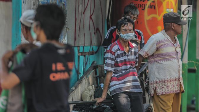 Warga memakai masker dan odol di wajah untuk menghindari sisa gas air mata pasca bentrok massa dengan aparat di Palmerah, Jakarta, Kamis (26/9/2019). Banyak masyarakat yang melintas dan warga sekitar perih pada mata hingga bersin akibat sisa gas air mata. (Liputan6.com/Faizal Fanani)