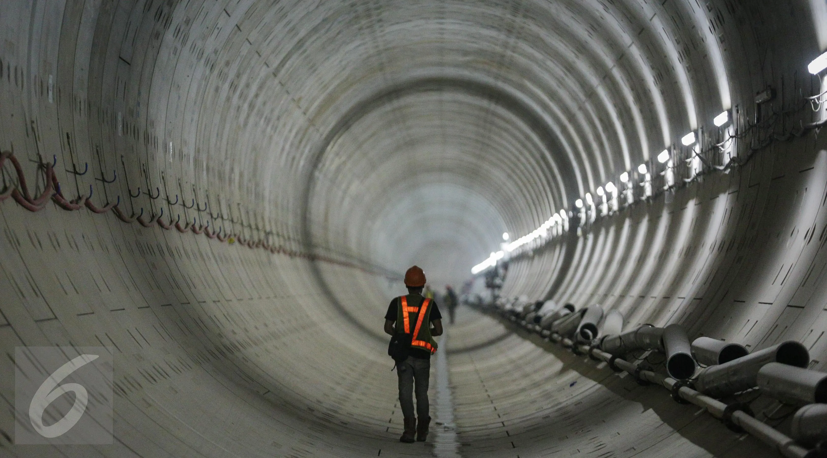 Seorang pekerja melintas di dalam terowongan mass rapid transit (MRT) yang masih dalam tahap penyelesaian di Jakarta (6/4). PT. MRT Jakarta mencatat progres pengerjaan telah mencapai 68,98 - 70 persen. (Liputan6.com/Faizal Fanani)