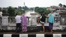 Sejumlah warga mengamati aliran sungai Ciliwung dari atas flyover di Jakarta Timur, Rabu (1/1/2020). Banjir yang berasal dari luapan Sungai Ciliwung itu menjadi daya tarik tersendiri bagi sebagian pemotor yang melintasi di flyover tersebut. (Liputan6.com/Immanuel Antonius)