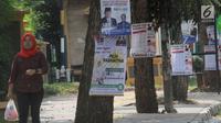 Pejalan kaki melintas dekat Alat Peraga Kampanye (APK) yang dipasang di pohon kawasan Ciater, Tangerang selatan, Senin (1/4). Pemasangan APK sejumlah caleg yang dipaku di pohon melanggar peratuan KPU Nomor 15 Tahun 2013 tentang tata cara pemasangan APK pemilihan umum. (merdeka.com/Arie Basuki)